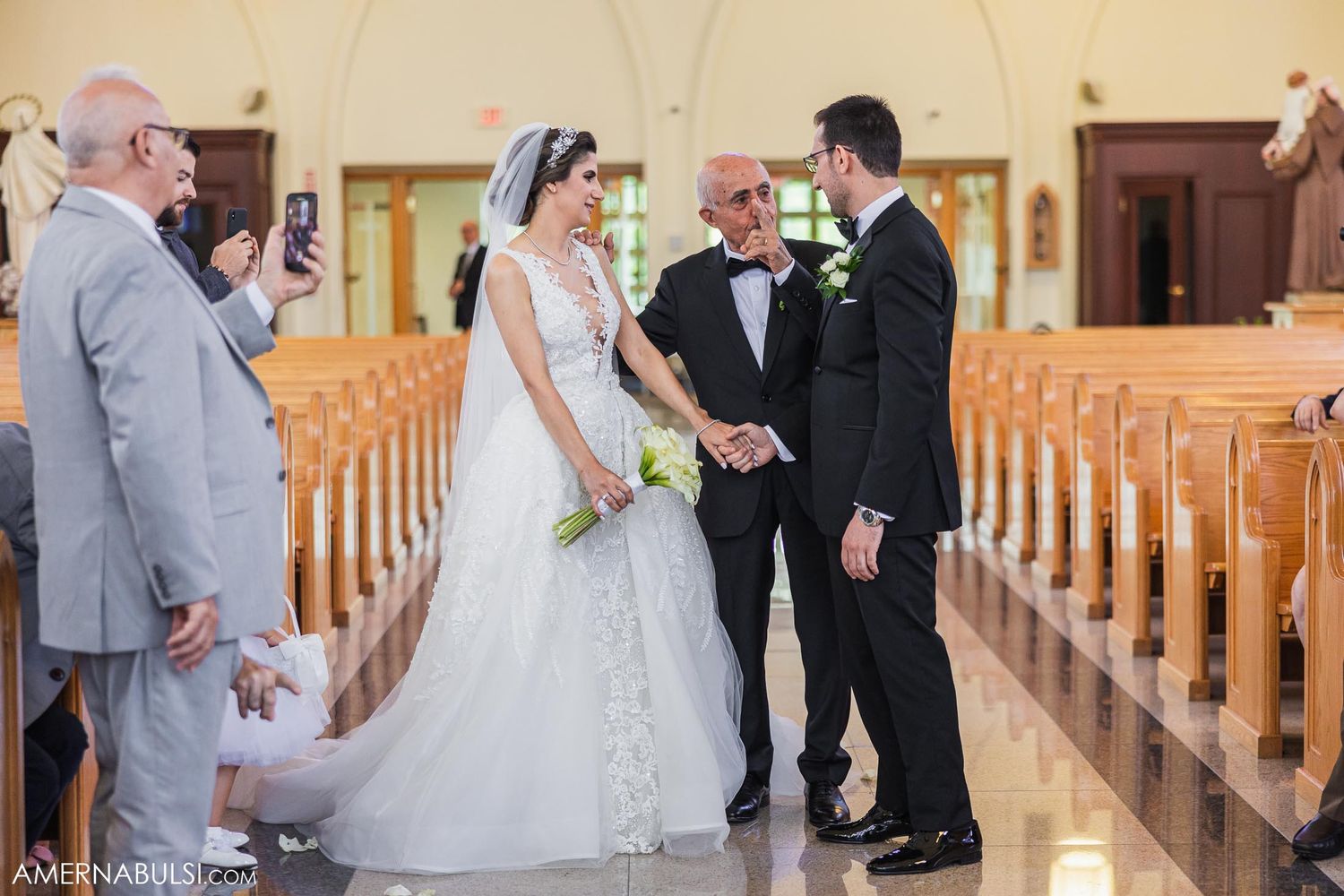 Wedding party members interact during a ceremony in an elegant church setting.