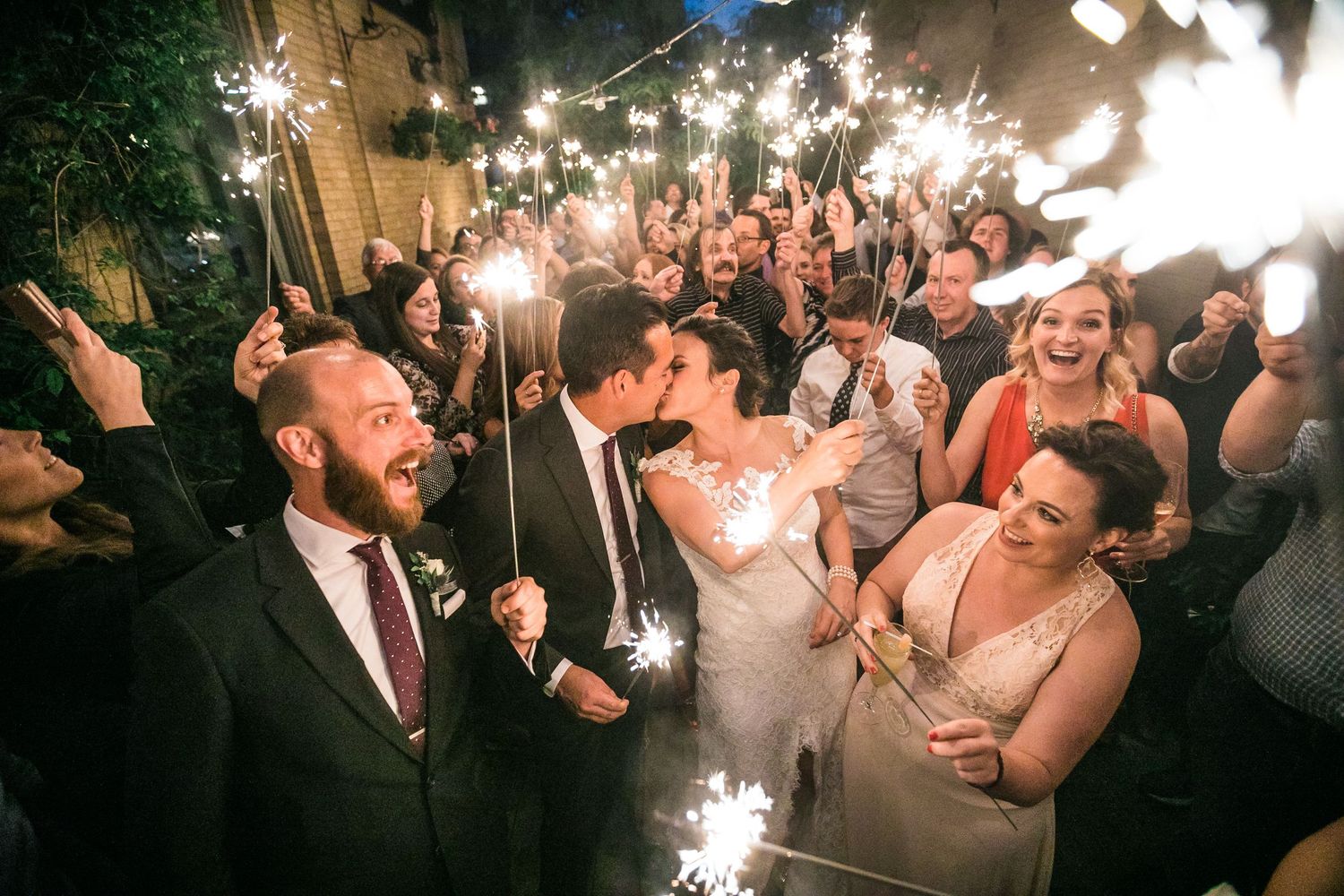 Wedding celebration with sparklers as guests surround the happy couple.