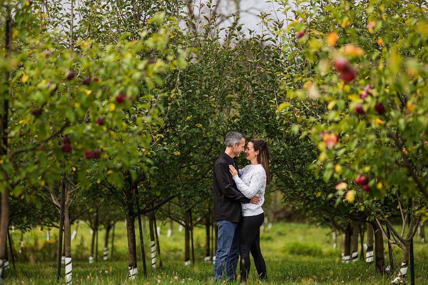 Couple sharing a moment in an autumn apple orchard.