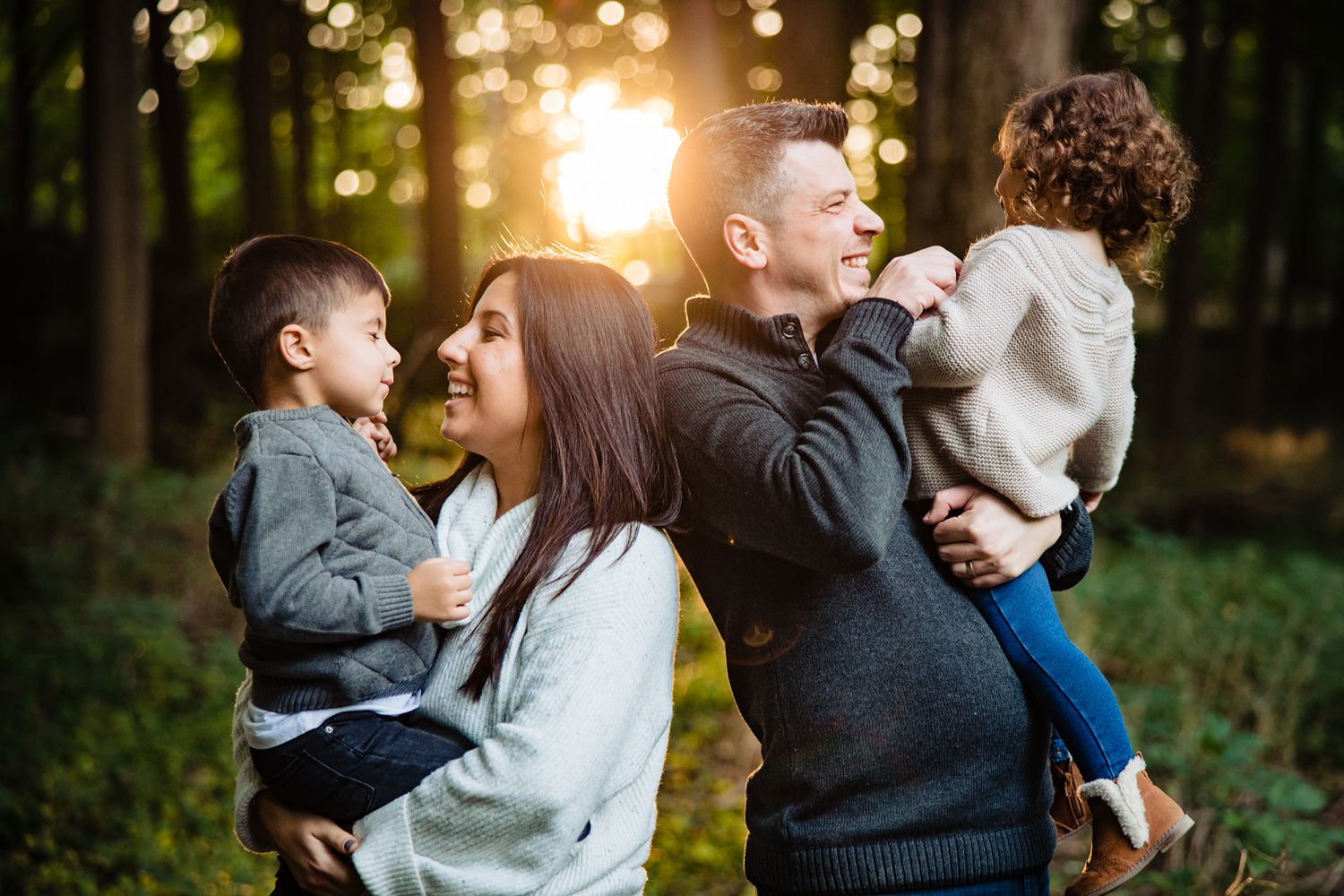 Family sharing a joyful moment together in a sunlit forest setting.