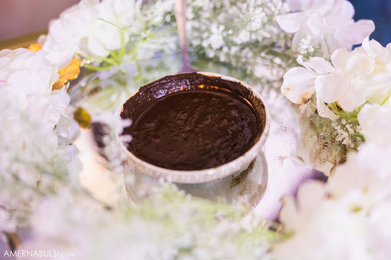 Chocolate dessert cup surrounded by delicate white flowers and floral arrangements.
