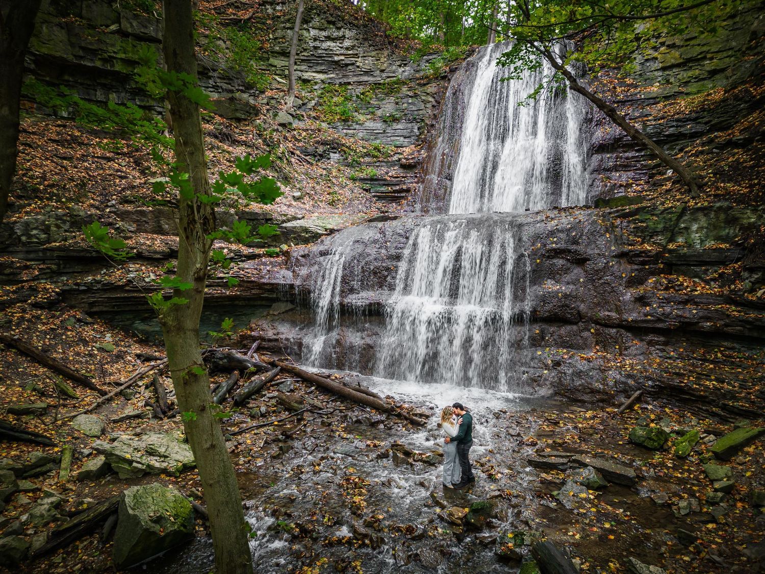 A cascading waterfall forms backdrop for an intimate moment between a couple.