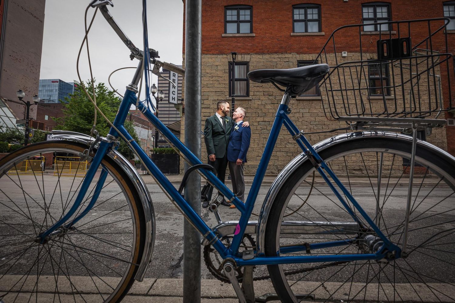 Vintage blue bicycle parked against brick building in urban setting.