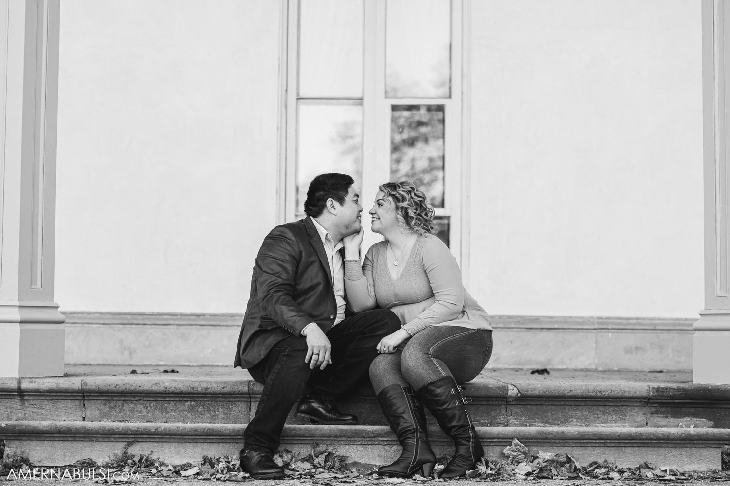 A romantic black and white photo of a couple sitting close together on stone steps.