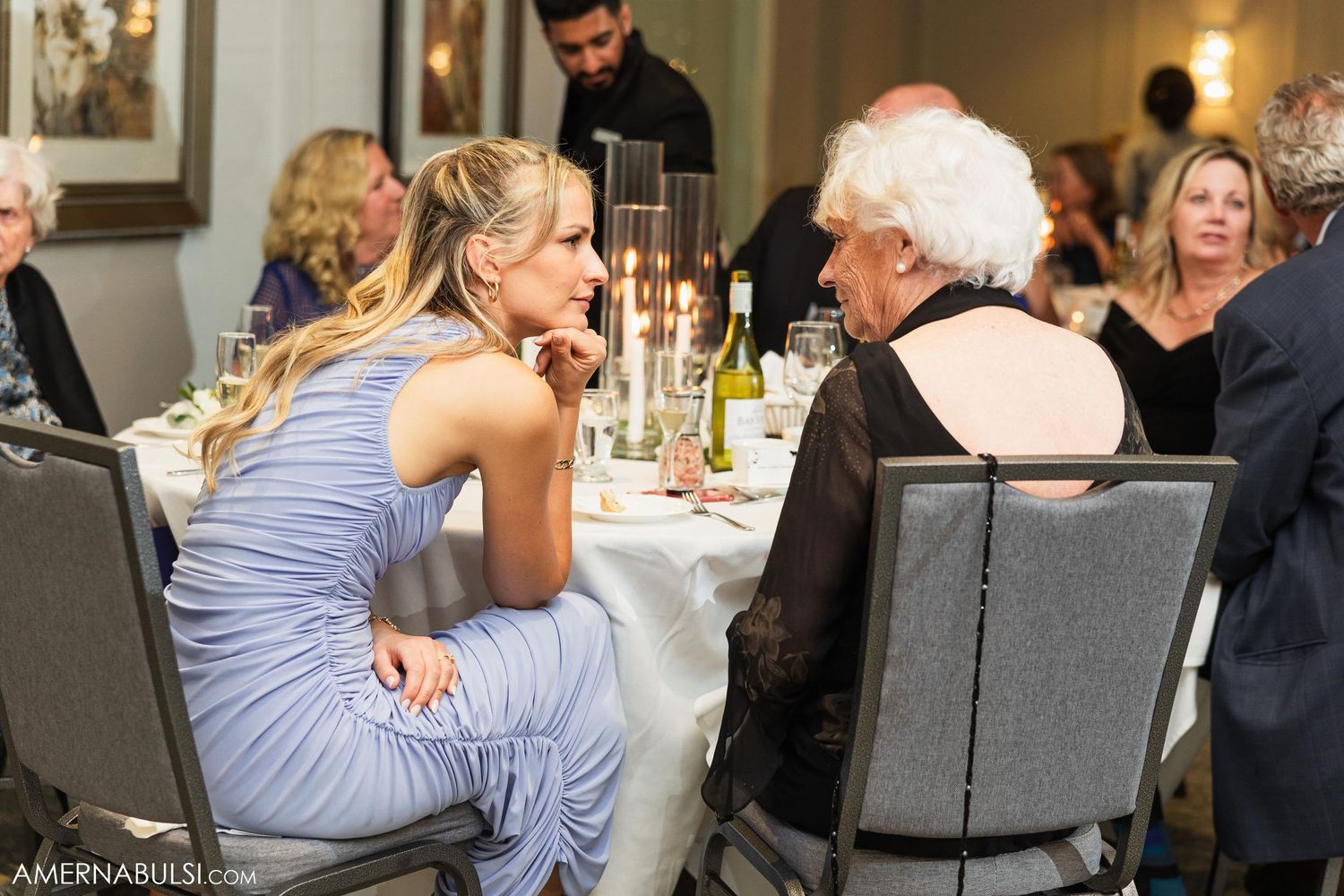 Wedding guests engaged in conversation at elegant reception dinner table.