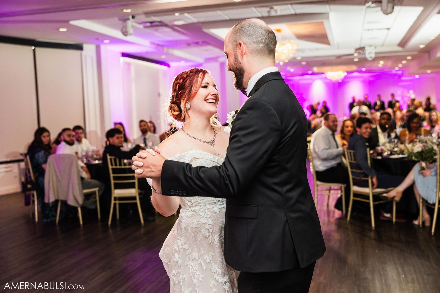 A romantic first dance at a wedding reception with purple accent lighting.