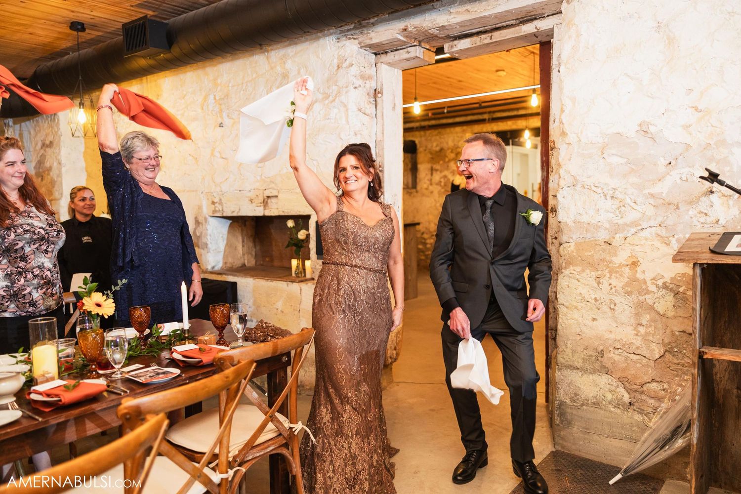 Wedding party members making grand entrance into rustic reception venue.