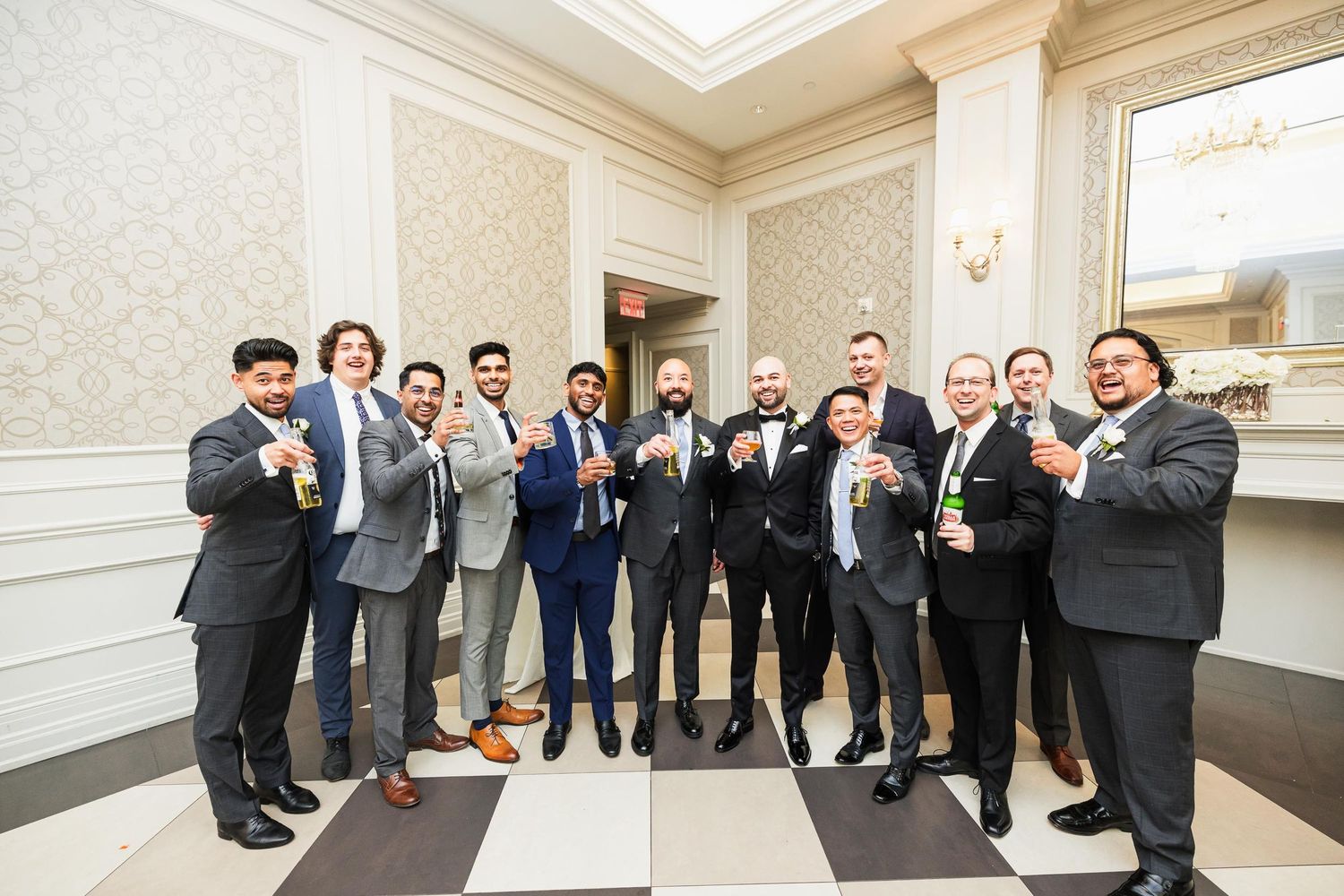 Groomsmen in formal suits pose together for group photo at wedding.