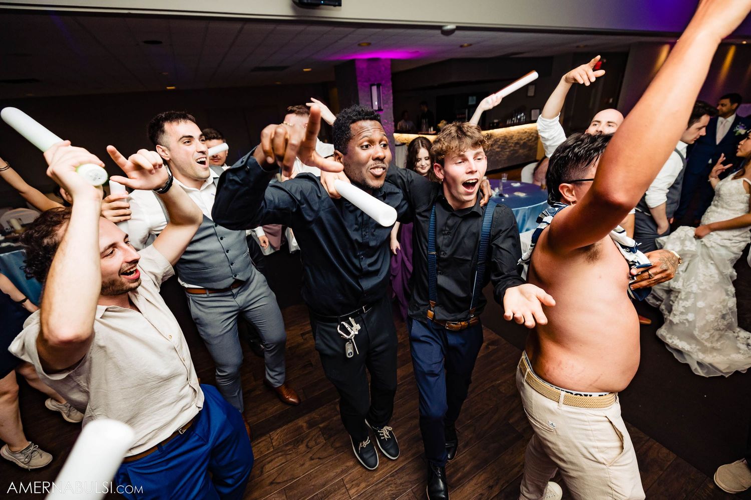 Wild dance party scene at wedding reception with guests jumping and celebrating.