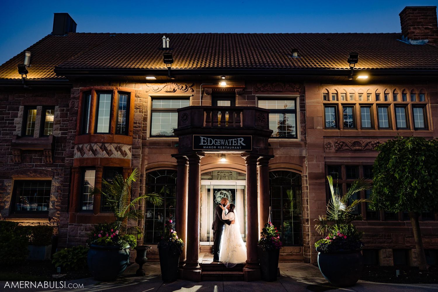 Wedding photograph showing a couple in a doorway of a rustic brick building at night.