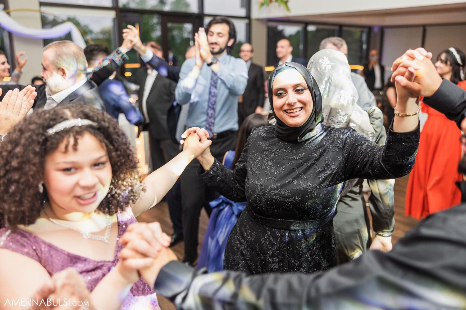 Wedding guests dancing and celebrating with joyful expressions at a reception party.