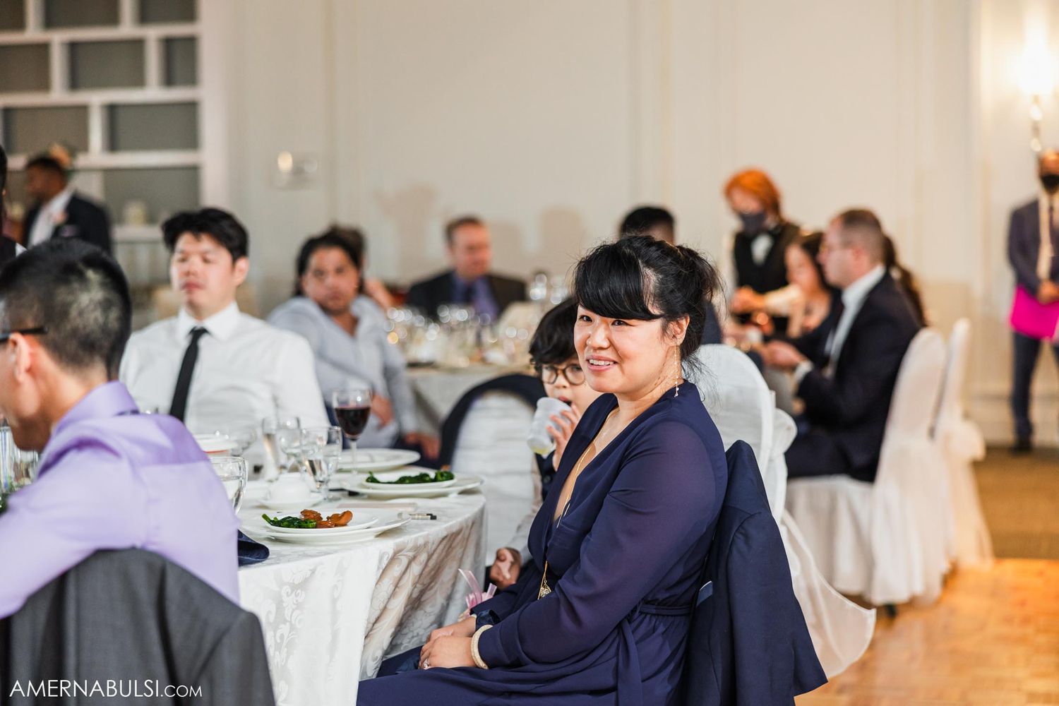 Wedding guests seated at round tables during dinner reception.
