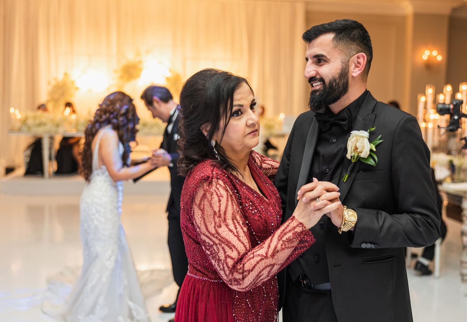 Wedding guests dance together during reception celebration with warm lighting and elegant decor.