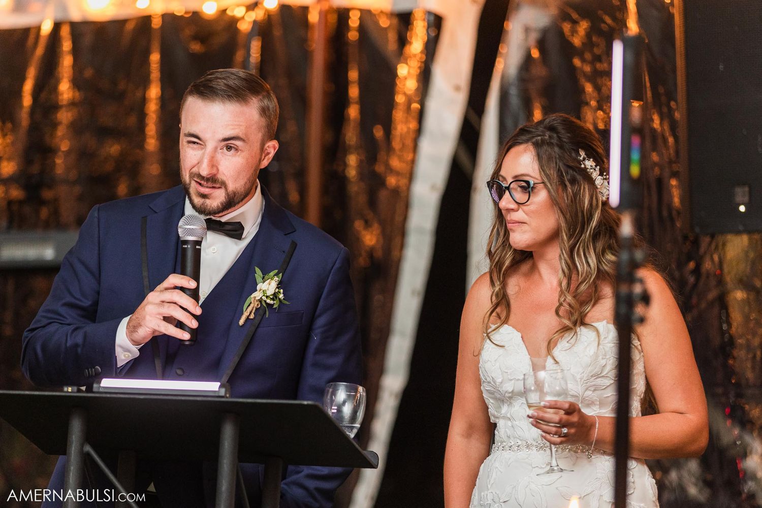 Couple sharing smiles while delivering wedding toasts at their outdoor reception.