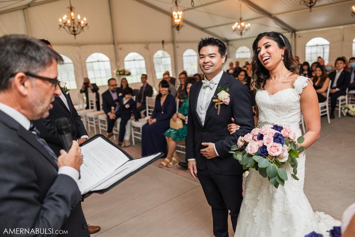 A joyful moment during wedding vows in an elegant reception venue with chandeliers.