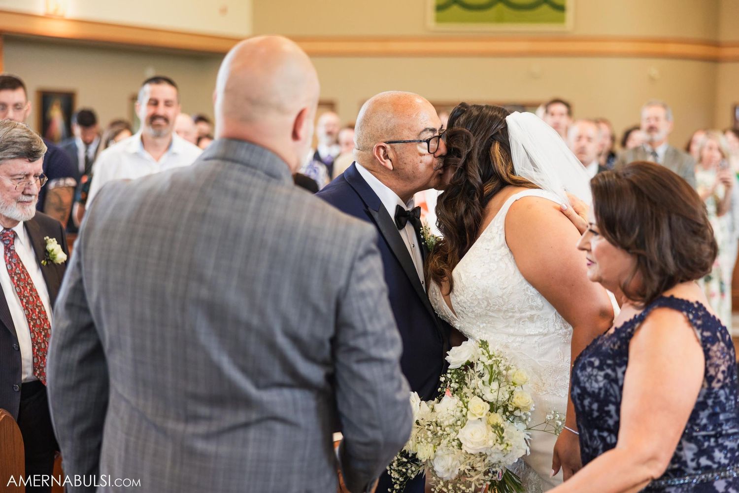 A touching moment during a wedding ceremony as guests look on with joy in a warmly lit venue.
