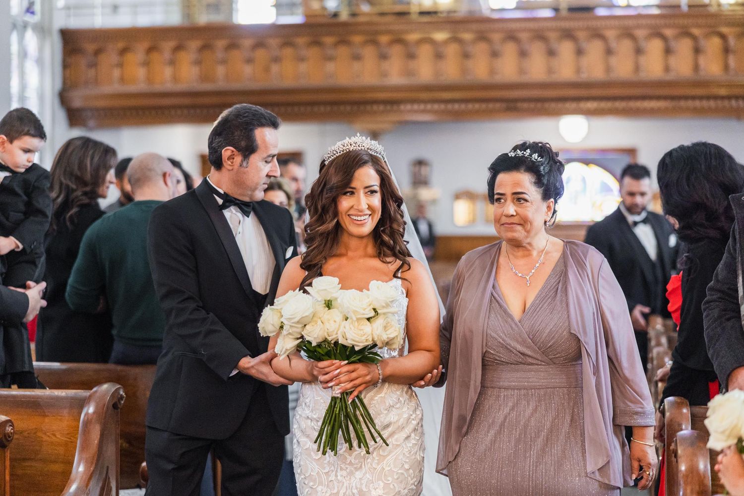 A wedding party processes through the church with guests in formal attire.