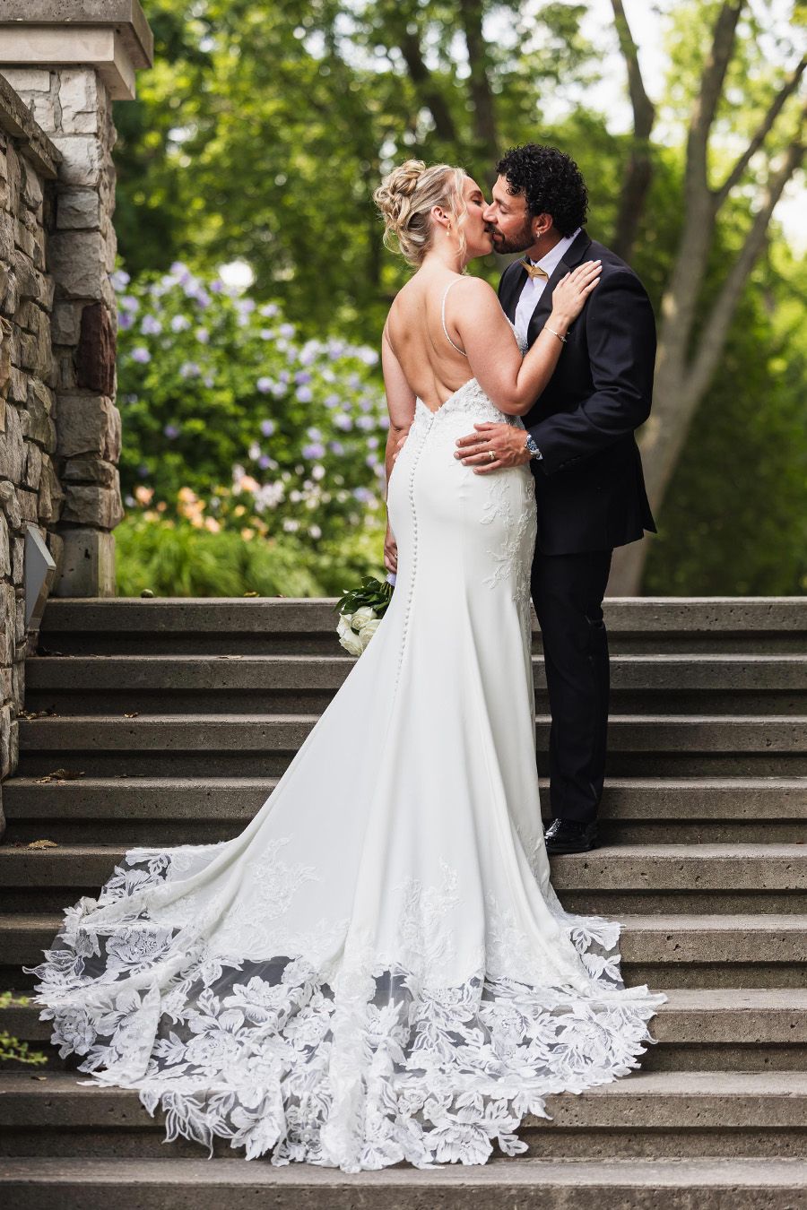 Romantic wedding couple portraits on stone steps with a stunning lace-trimmed bridal gown.