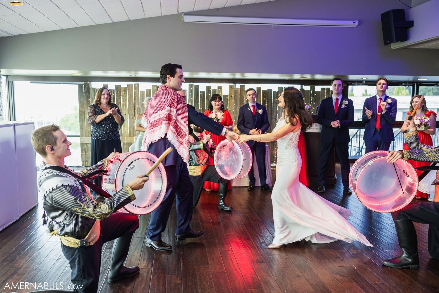 Drummers create energetic entertainment during wedding celebration in purple-lit venue.