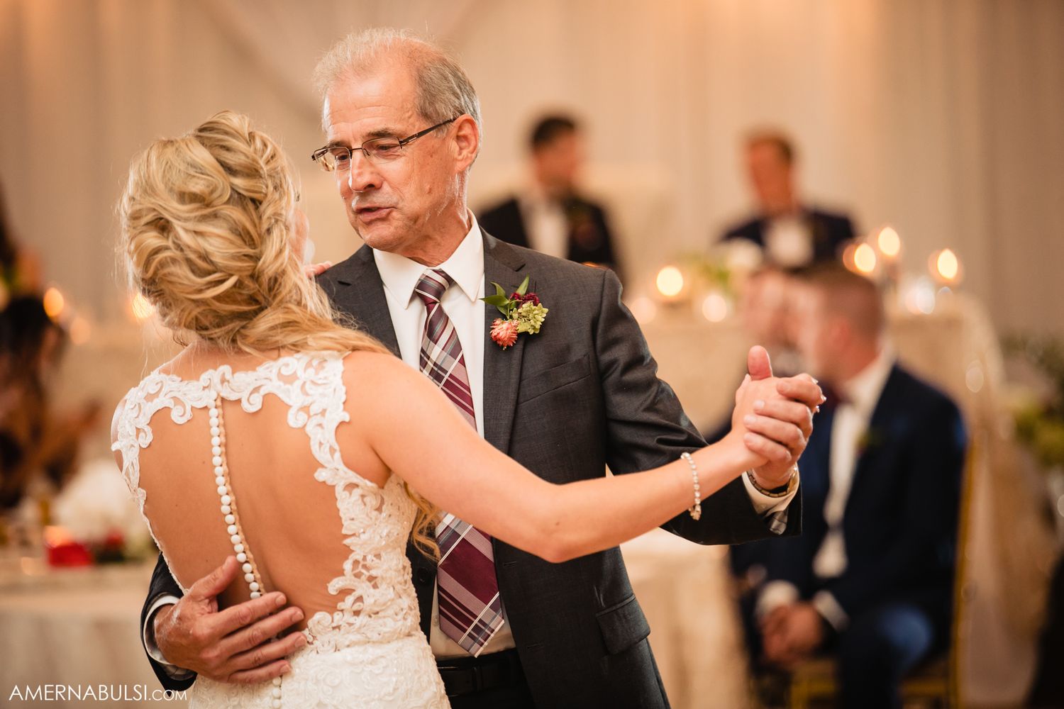 A couple shares an intimate dance moment during a wedding reception in an elegant ballroom.