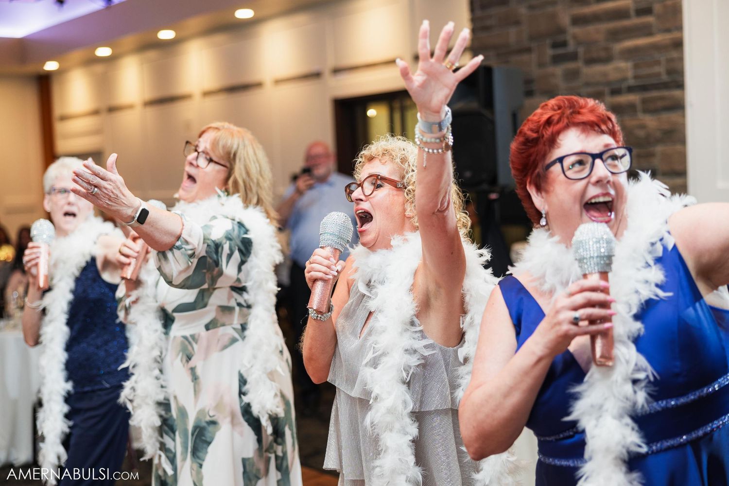 Wedding guests dance and sing with feather boas during reception entertainment.