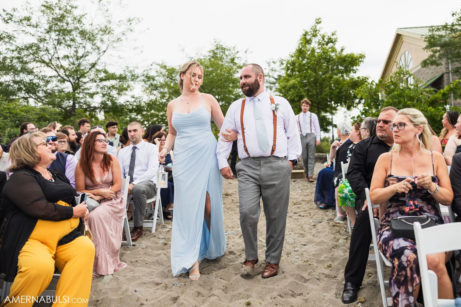 Wedding guests dancing and celebrating on a beach during sunset festivities.