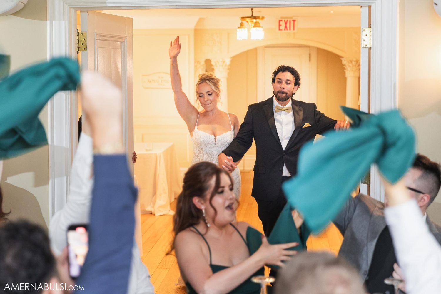 A joyous wedding reception entrance with guests waving green napkins in celebration.