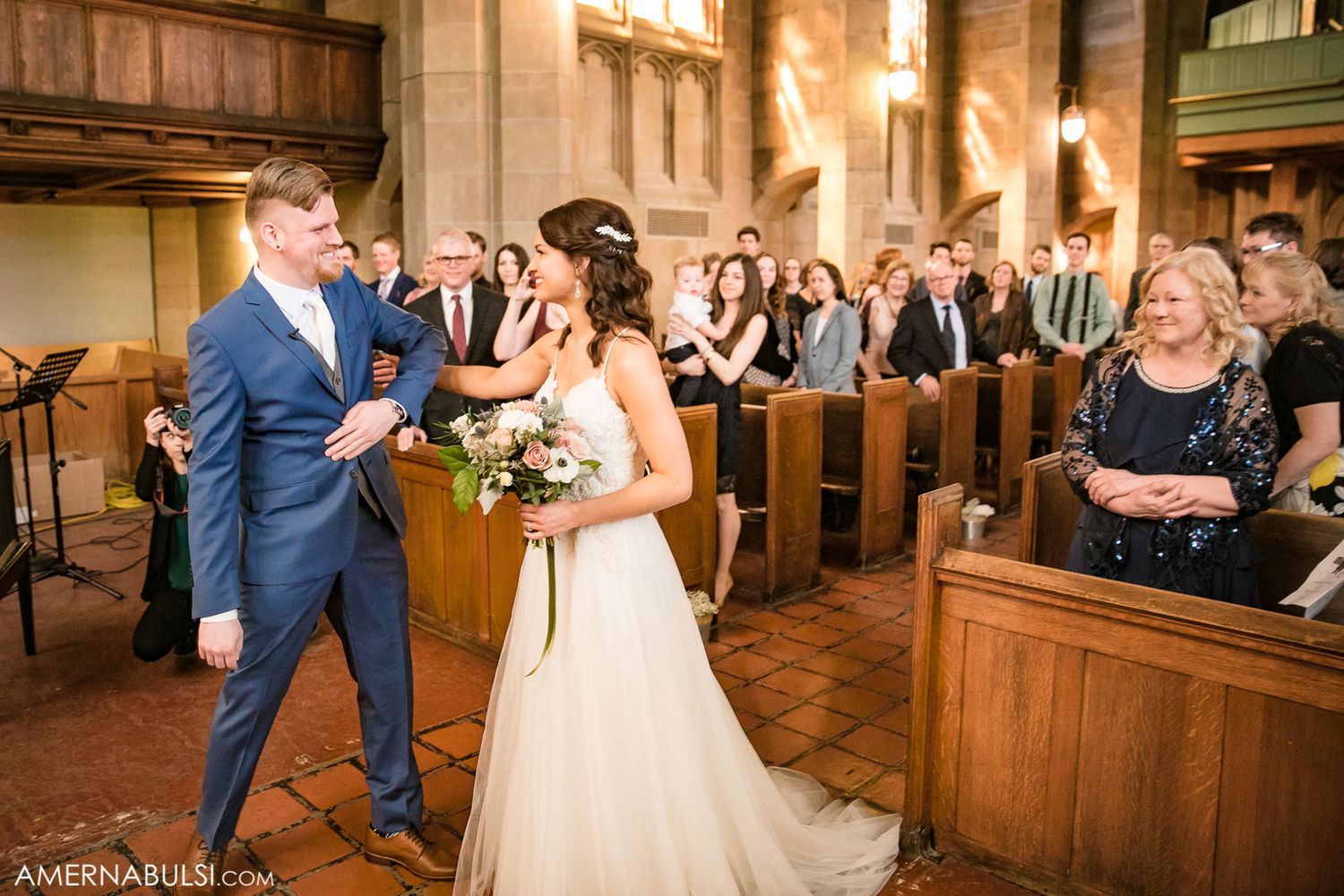 Wedding guests watch and smile as a couple shares their first dance in an elegant church venue.