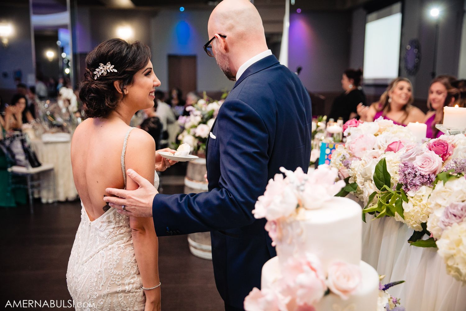 Couples dancing together at an elegant wedding reception with pink floral decorations and ambient lighting.