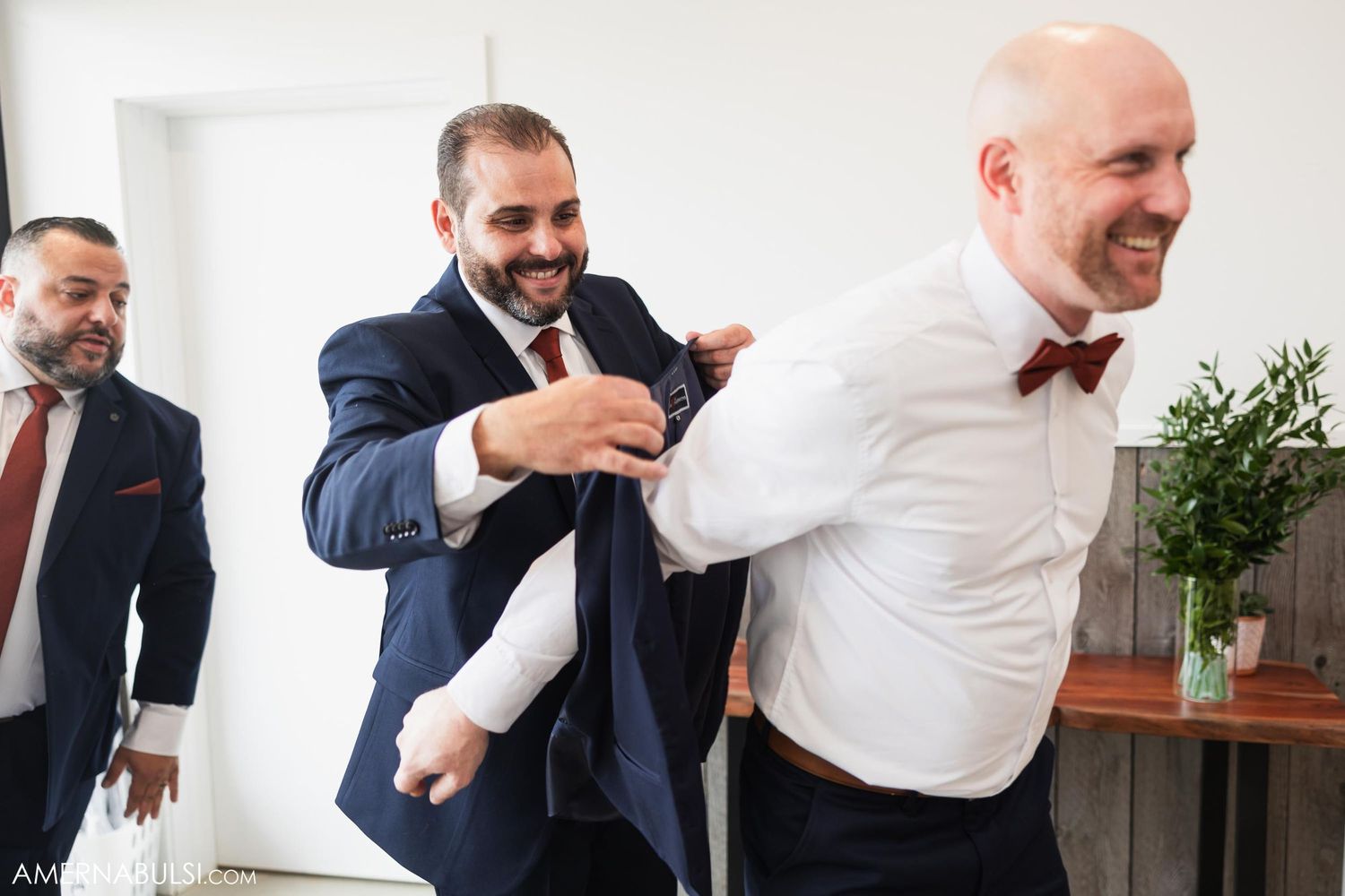 Candid moment of groomsmen laughing and joking during wedding preparations.