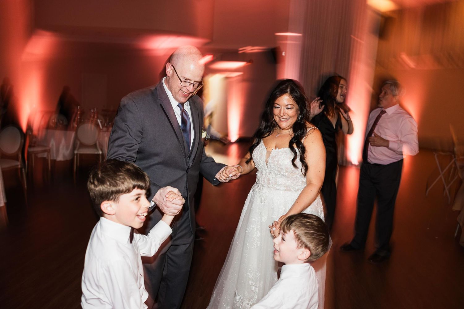 Wedding reception scene with dancing and warm lighting in elegant ballroom setting.