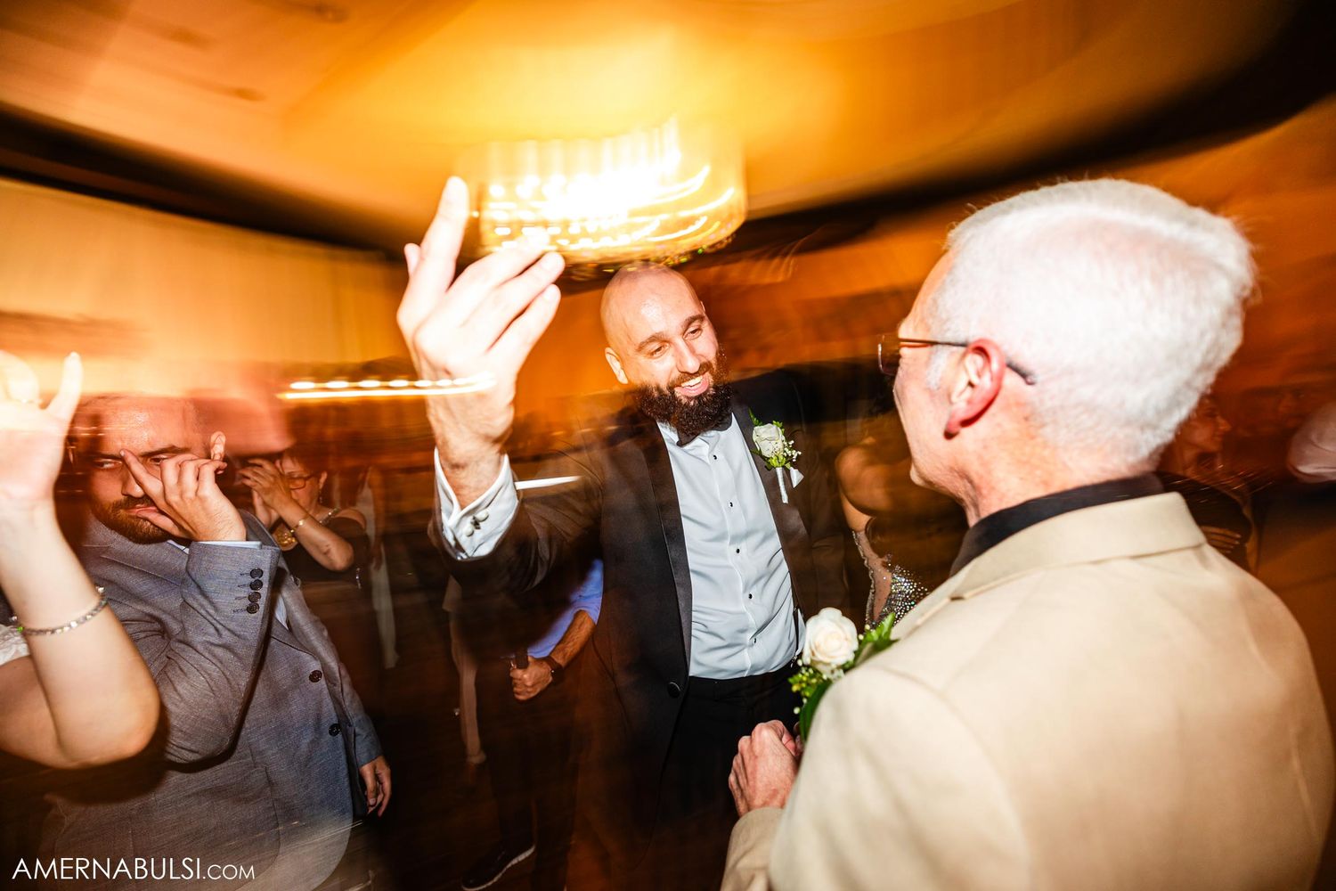 Wedding guests celebrate enthusiastically on the dance floor during the reception.