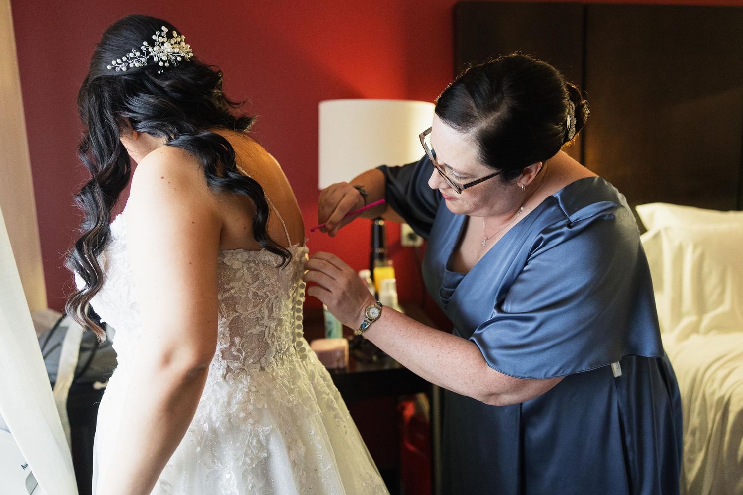 Final adjustments being made to the back of an ornate wedding dress.