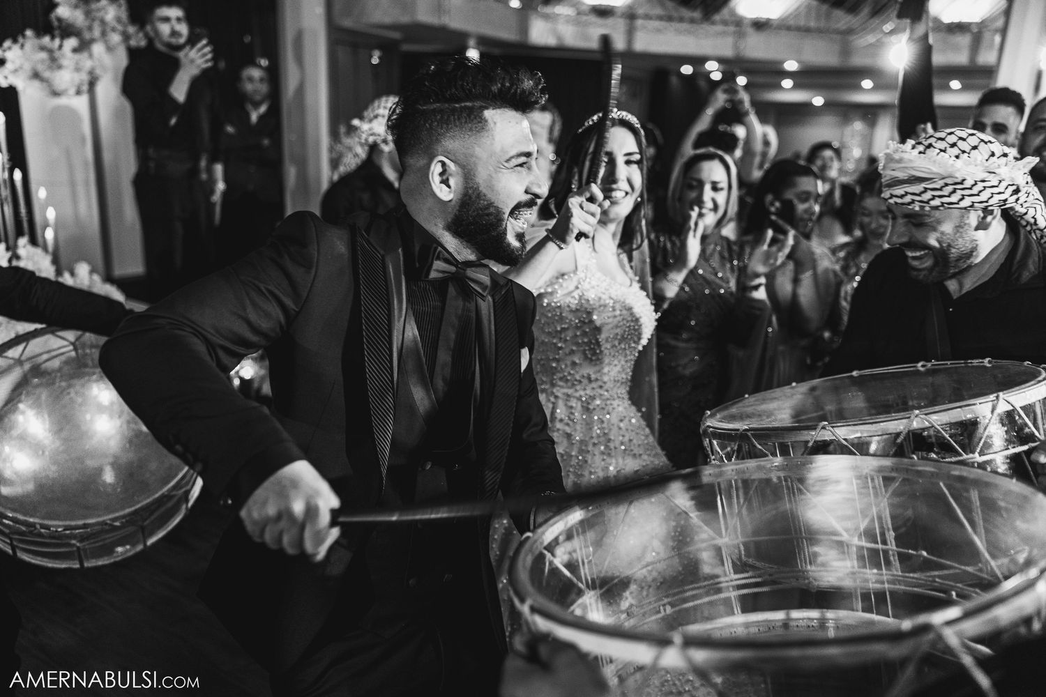 Black and white shot of wedding guests dancing and celebrating at a reception party.