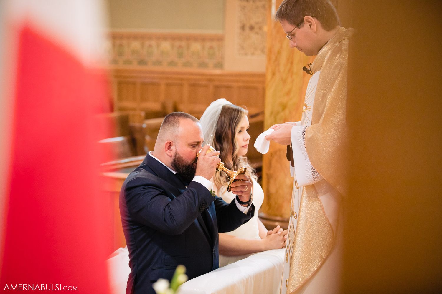 Wedding ceremony moment in an ornate church with warm amber lighting.