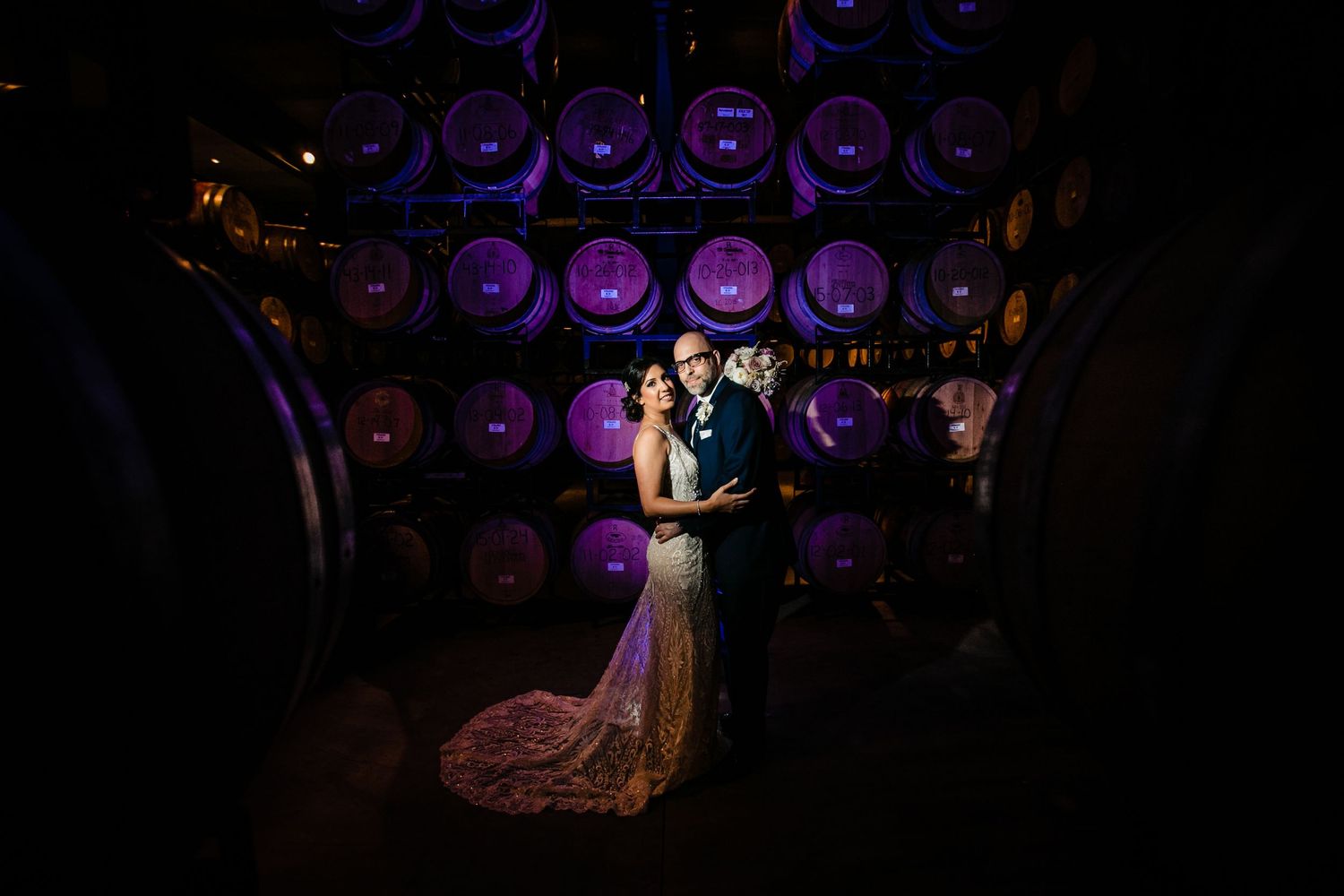 A couple dancing in formal attire under purple stage lighting at an elegant event venue.
