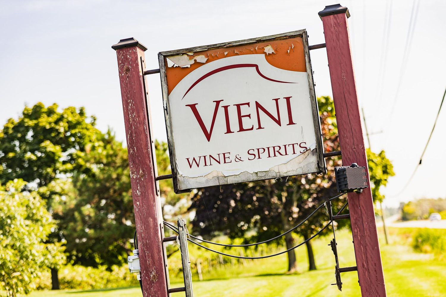 Vieni Wine and Spirits wooden business sign mounted on red posts.