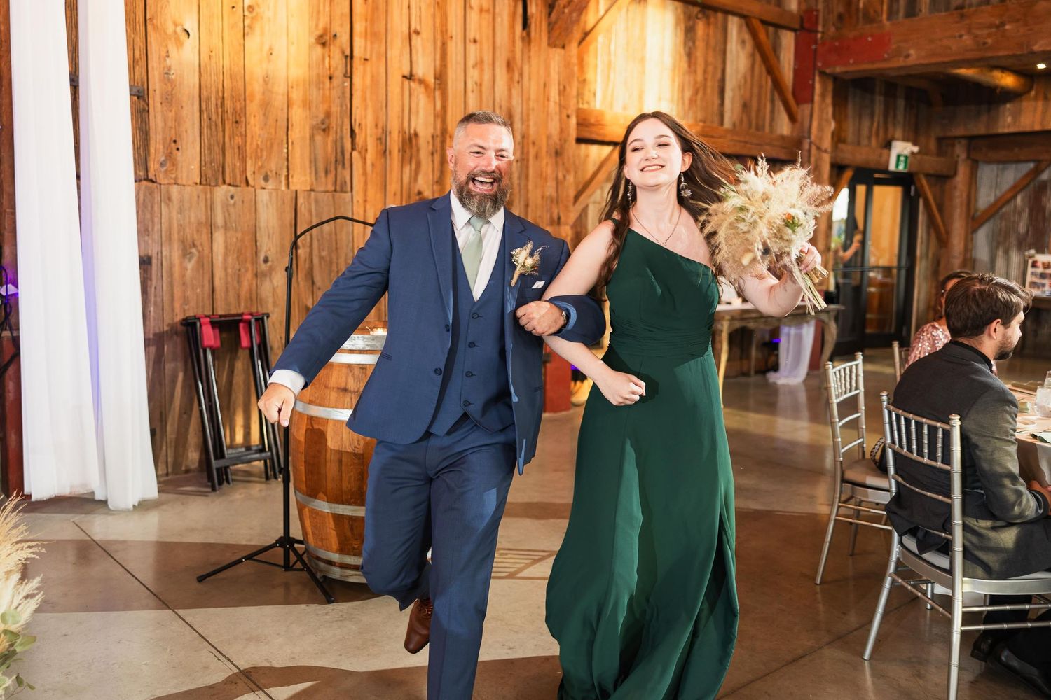 Dancing duet in elegant attire at a rustic barn-style venue.
