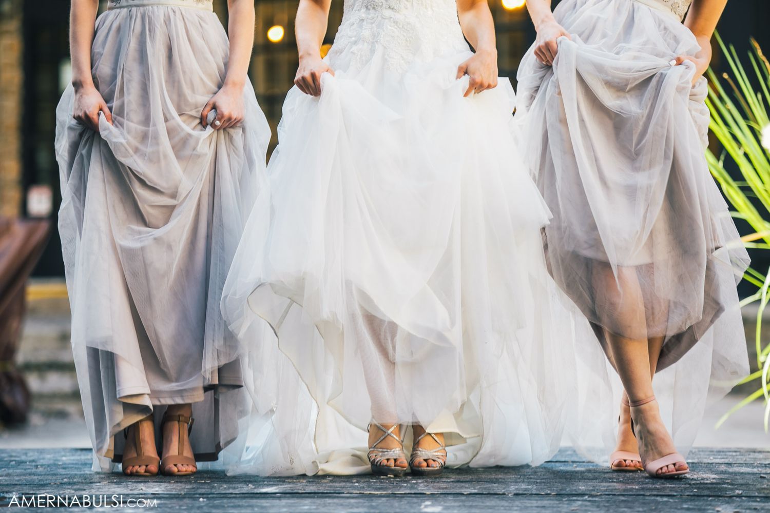 Row of formal dresses and gowns shown from waist down during wedding celebration.