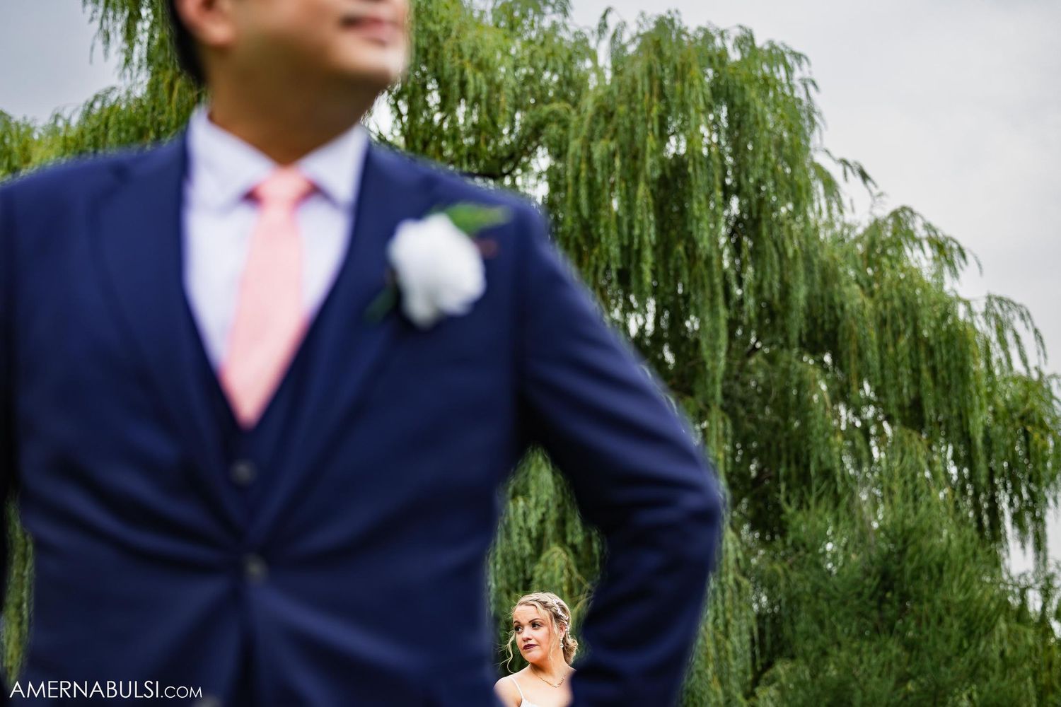 Creative wedding portrait with groom in foreground and bride in background.