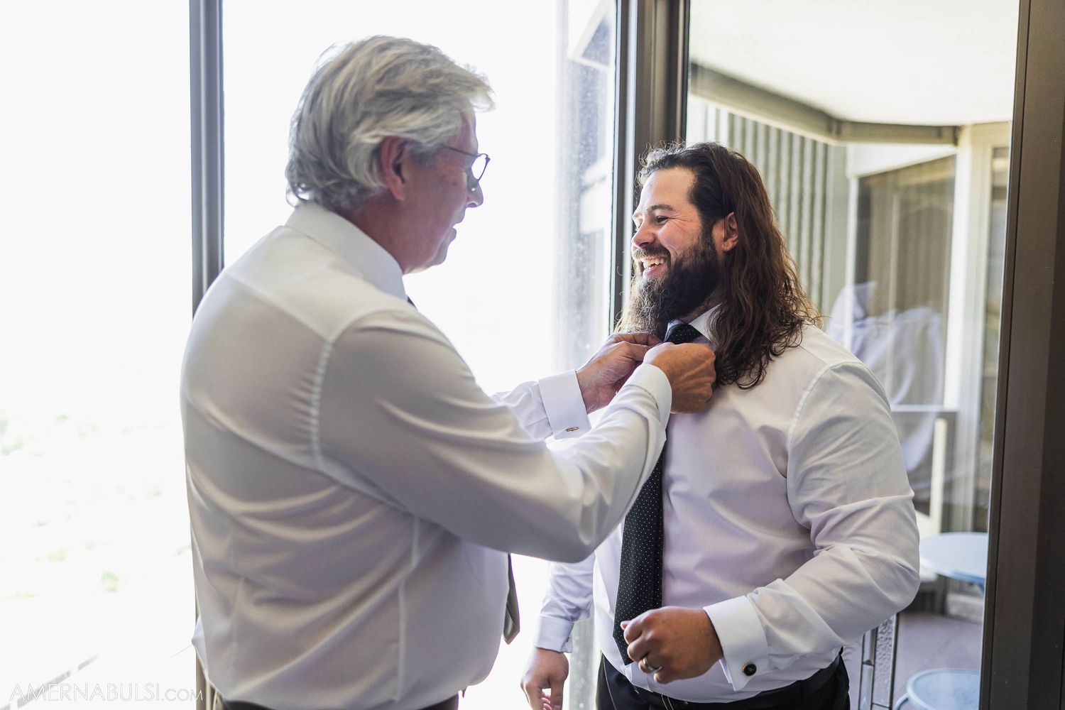 Two people share an intimate moment getting ready before a wedding ceremony.