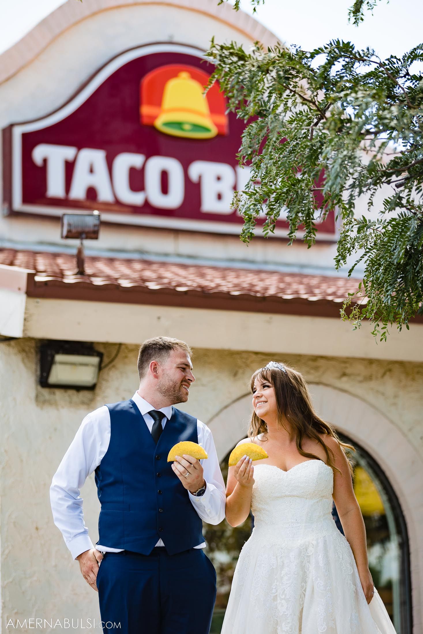 Happy newlyweds enjoying tacos in front of a Taco Bell restaurant sign.