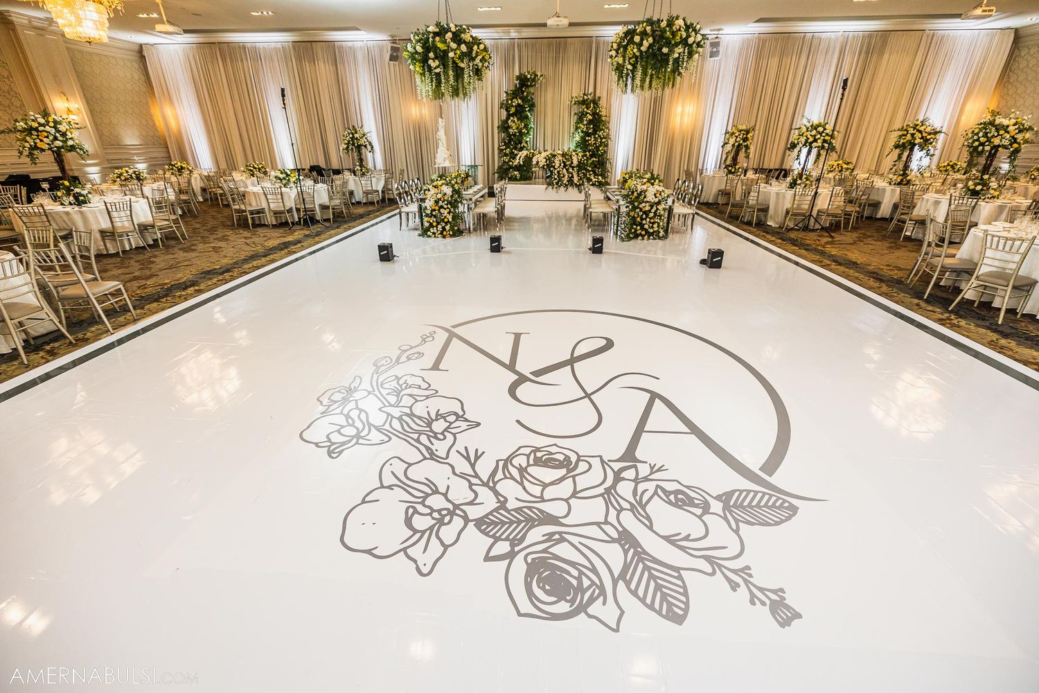 White dance floor with custom monogram and floral design in an elegant ballroom setting.