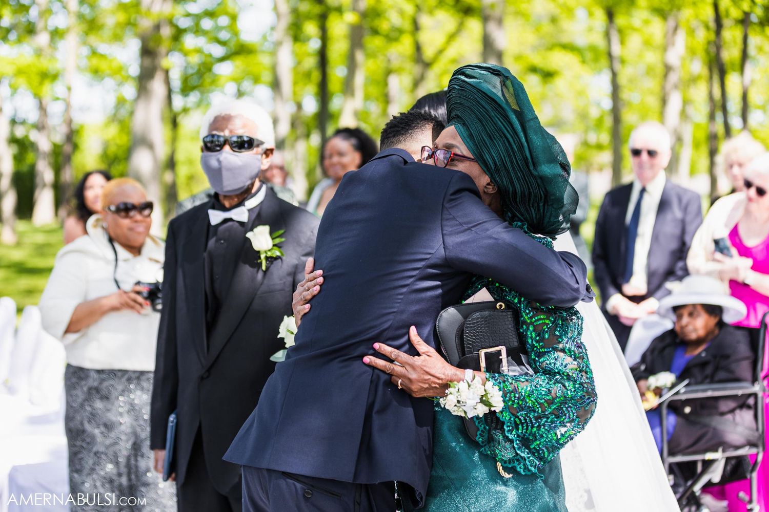 Emotional embrace during outdoor wedding celebration with guests watching.