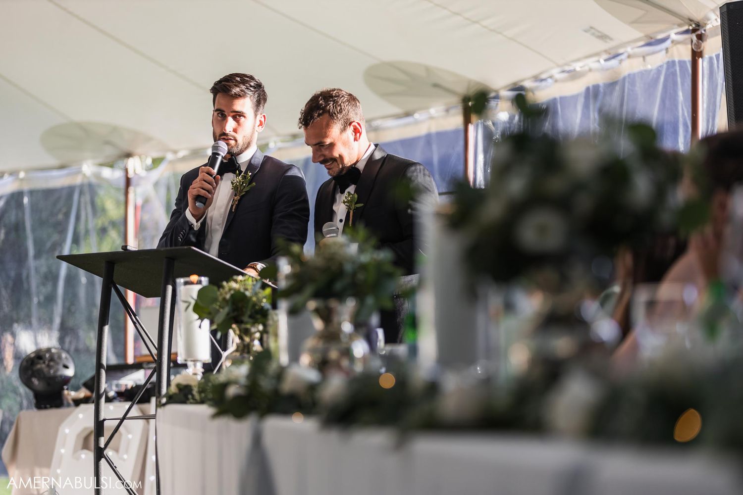 Couple reacts emotionally to wedding speeches while seated at decorated head table.