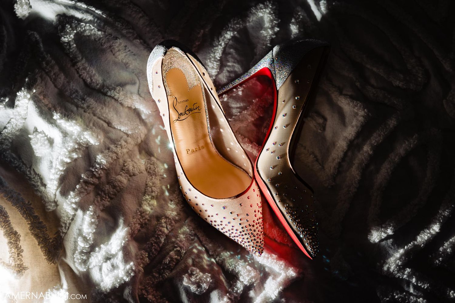 Elegant crystal-studded wedding shoes photographed with dramatic lighting and dark background.