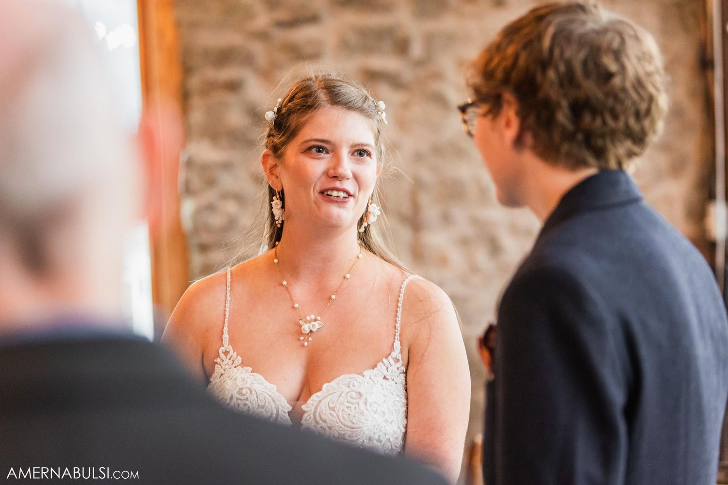 A couple exchanges vows in front of a stone wall during an intimate wedding ceremony.