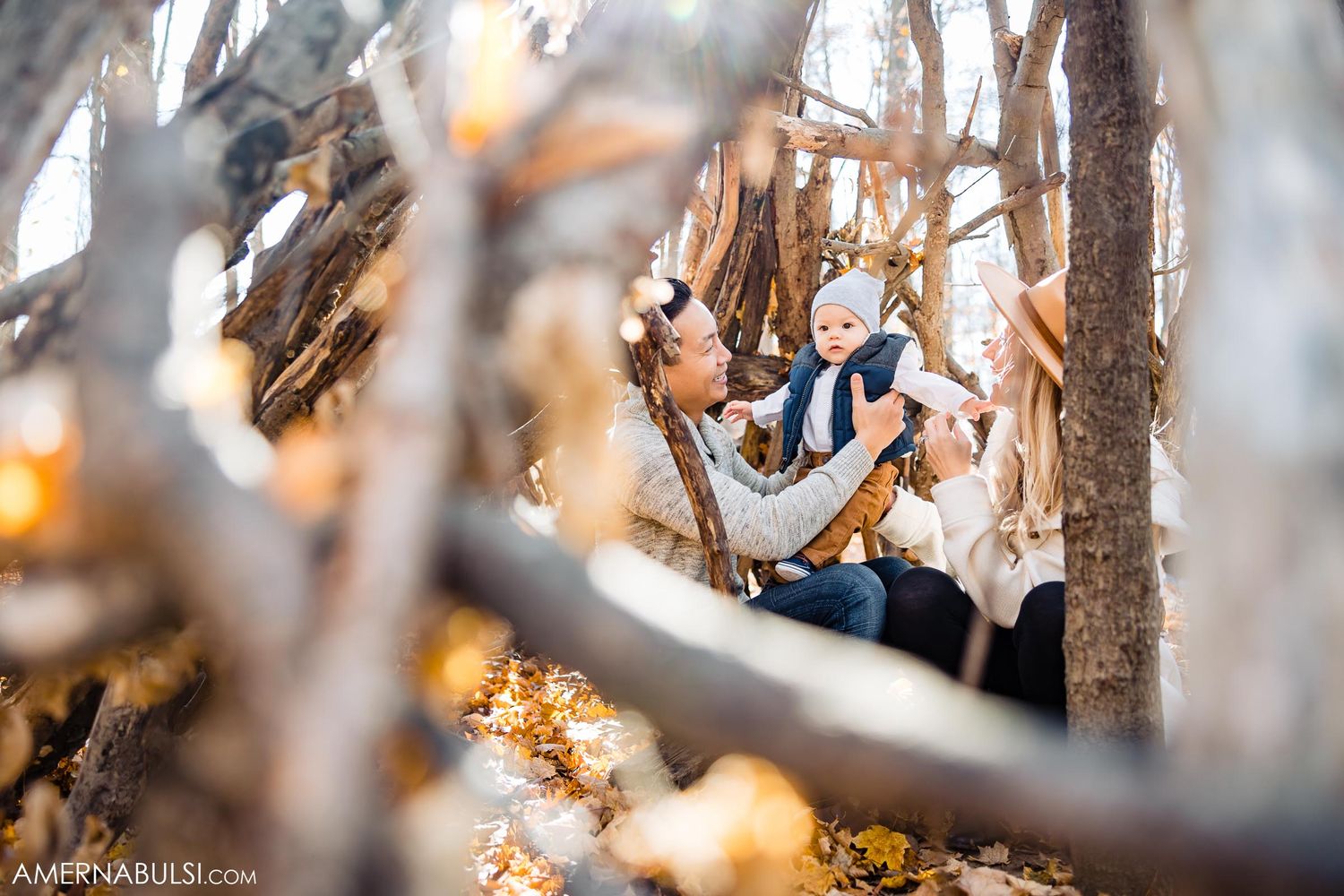 Artistic through-the-branches shot of couple in fall forest setting.
