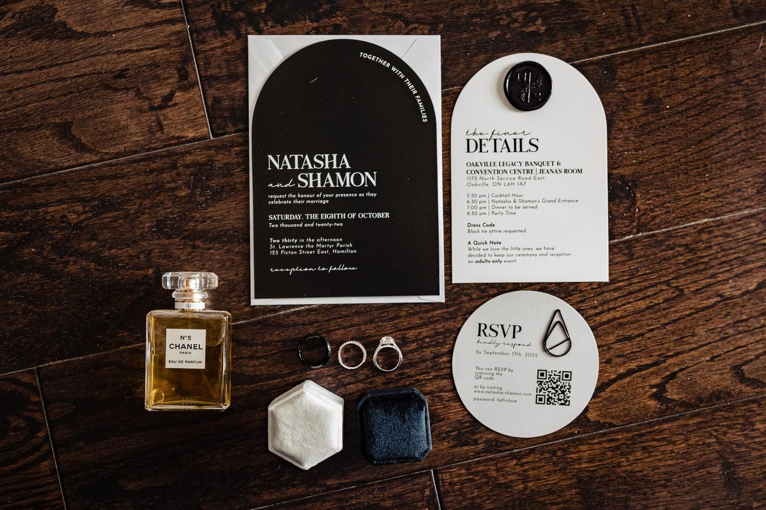 Modern wedding invitation suite with perfume bottle and rings on wooden surface.