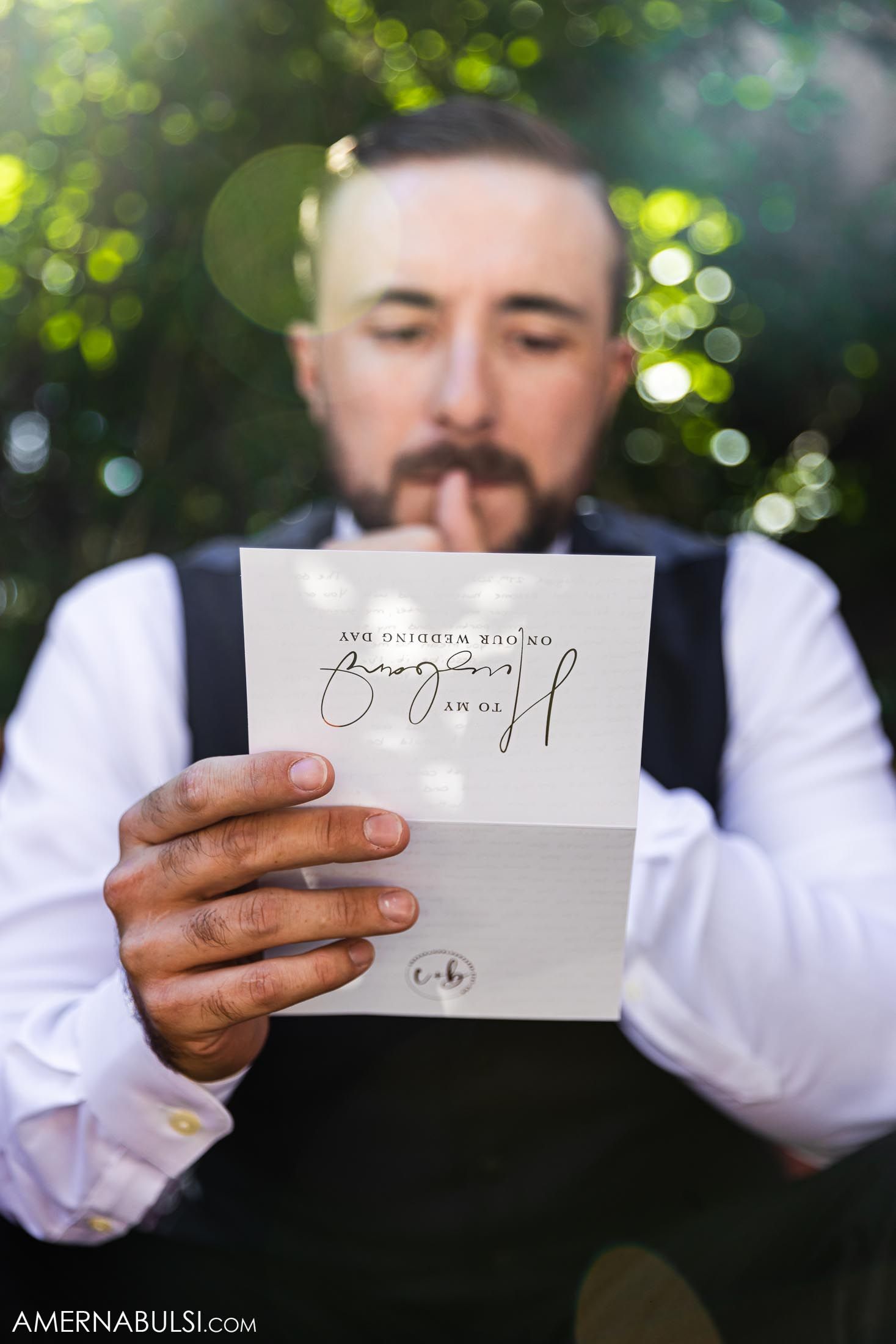 A person in formal attire holds a handwritten note with bokeh background effects.